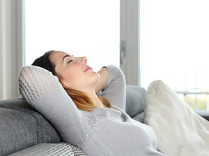 Happy relaxed woman resting on a couch at home