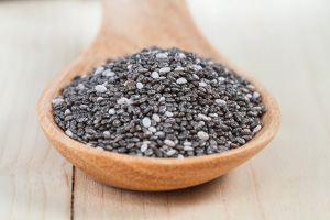 chia seeds in a wooden scoop on wood cup