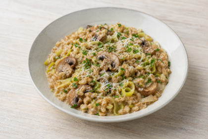 Dinkelrisotto mit gebratenen Champignons, Lauch und Petersilie in einer hellen Schale.