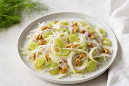Fenchel-Trauben-Salat mit Walnüssen und frischen Kräutern auf einem hellen Teller.