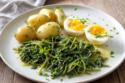 Gedünstete Weidenröschen-Sprossen mit kleinen Kartoffeln und halbierten Eiern auf einem Teller.