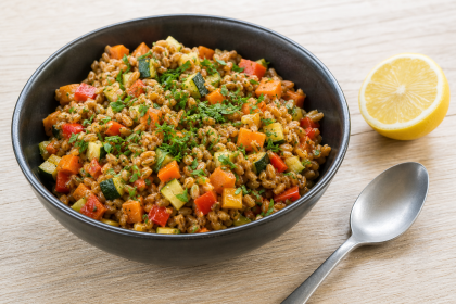 Grünkern-Gemüse-Pfanne mit Möhren, Paprika, Zucchini und Petersilie in einer Schale.