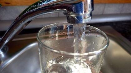 Ein Glas wird unter dem Wasserhahn mit Leitungswasser gefüllt