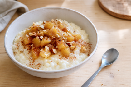 Schale mit Milchreis, Apfelkompott, Zimt und gerösteten Mandeln