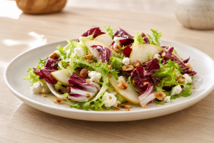 Radicchio-Endivien-Salat mit Birne, Ziegenkäse und gerösteten Haselnüssen auf einem Teller
