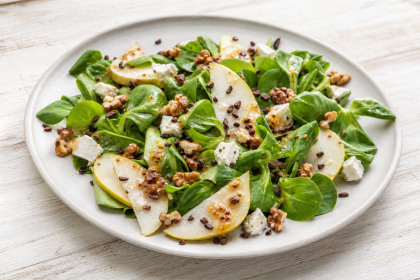 Wintersalat mit Birnenspalten, Ziegenkäse, Walnüssen und Kakaonibs auf einem Teller