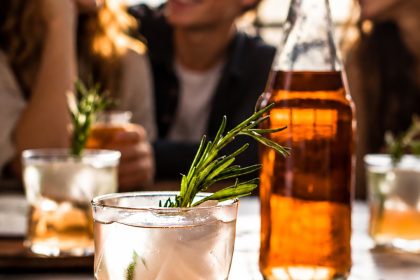 Alkoholfreier Rhabarber-Spritz vor einer Gruppe junger Menschen; vom VdF KI-bearbeitetes Pressebild
