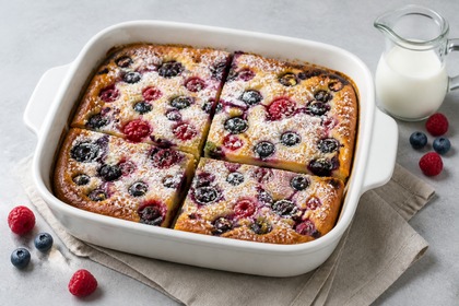 Goldbrauner Beeren-Ofenpfannkuchen mit Himbeeren und Heidelbeeren in einer weißen Auflaufform