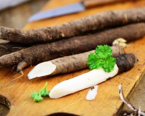 Ungeschälte und angeschnittene Schwarzwurzeln auf einem Holzbrett