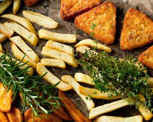Rösti, Pommes frites und Kartoffelecken auf einem Backblech mit Kräutern.