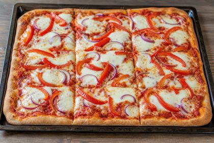 Goldbraun gebackene Emmer-Blechpizza mit Tomatensauce, Mozzarella, roter Paprika und roten Zwiebeln.
