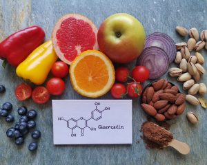 Obst, Gemüse und Nüsse neben einer Darstellung der Quercetin-Struktur