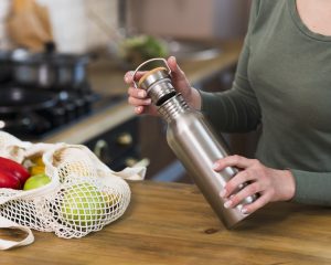 Eine Person öffnet eine wiederverwendbare Trinkflasche aus Edelstahl.