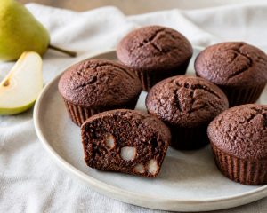 Dunkle Kakao-Birnen-Muffins auf einem Teller, einer davon aufgeschnitten