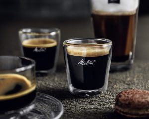 Espresso und Kaffee in Melitta-Gläsern neben einem Gebäckstück.