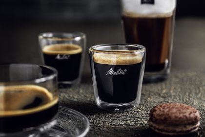 Espresso und Kaffee in Melitta-Gläsern neben einem Gebäckstück.