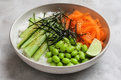 Reisschale mit Gurke, Möhre, Edamame, Nori-Streifen, Sesam und Limette