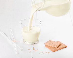 Pflanzliches Getränk mit Mandel-Zimt-Aroma neben Mandeln und Gebäck