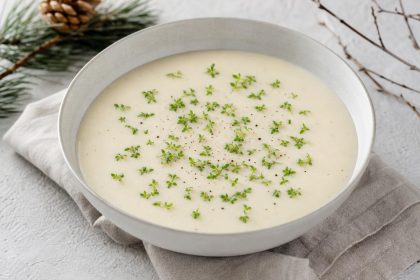 Helle Schwarzwurzel-Kartoffel-Cremesuppe mit frischer Kresse und schwarzem Pfeffer in einer Schale.