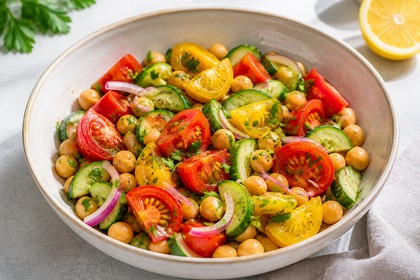 Salat mit roten und gelben Tomaten, Gurke, Kichererbsen und roten Zwiebeln